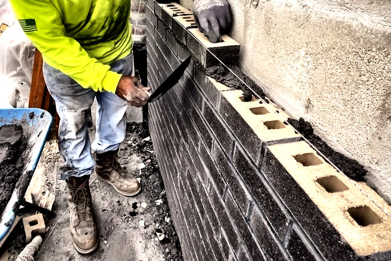 Mason laying dark brick veneer against new block