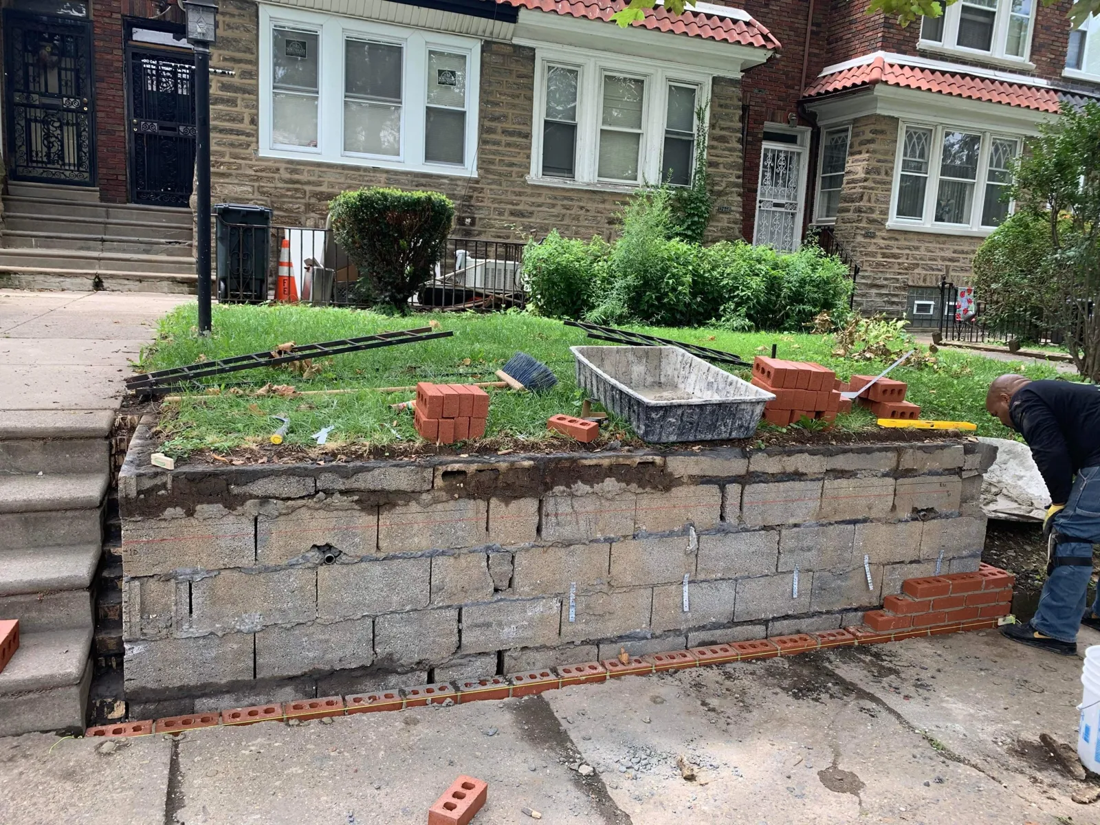 Before: cracked concrete block retaining wall with new brick starting at the base